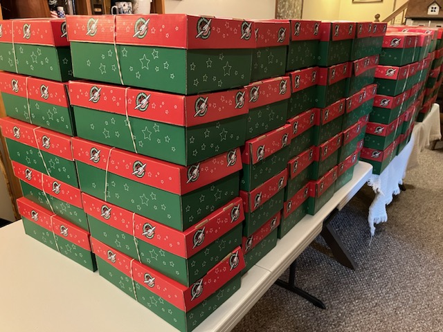 Table full of approximately 166 red and green operation Christmas child shoeboxes
